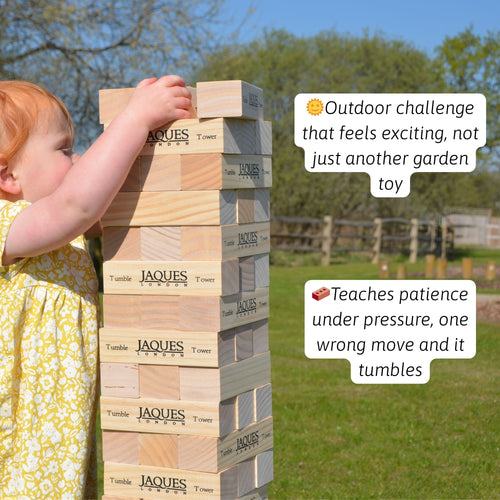 Young child playing giant wooden tumble tower stacking game outdoors 