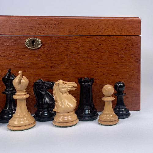 Wooden chess pieces in front of a wooden chessboard box on a white background 