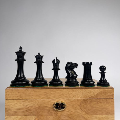 Set of black chess pieces on a wooden box with a grey background 