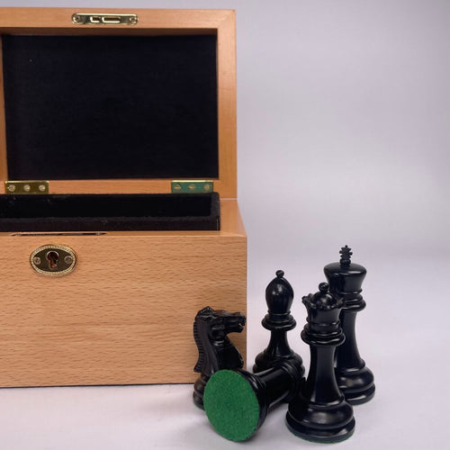 A group of black chess pieces next to an open beech box. 