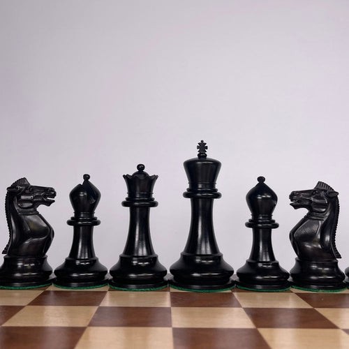 Set of black chess pieces on a wooden chessboard with a light gray background 