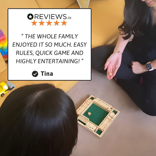 Two people sitting on the floor playing the wooden shut-the-box game, with a five-star review overlay describing it as easy to learn, quick, and highly entertaining. 