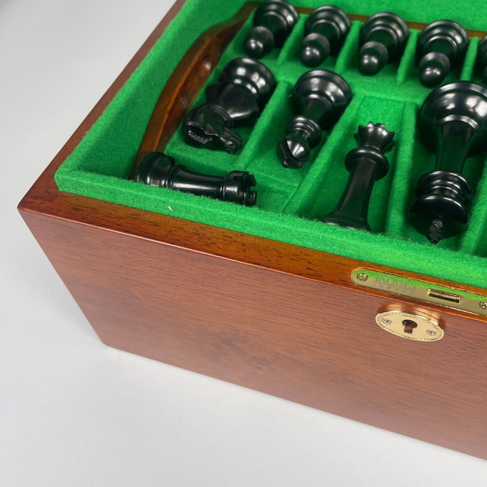 Black chess pieces in a wooden box with green felt lining 