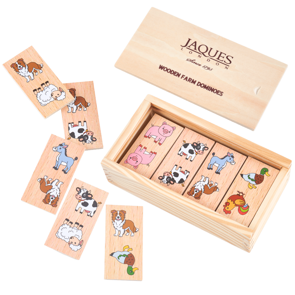 Wooden farm domino game set by Jaques London, showing the open wooden box with animal-themed domino tiles and several loose tiles arranged on a solid green background. 