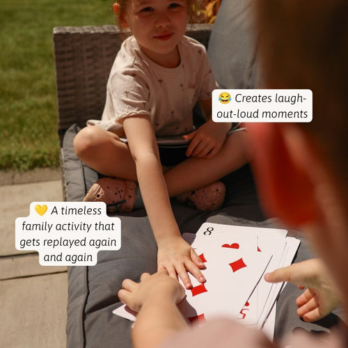 Child playing cards with an adult outdoors 