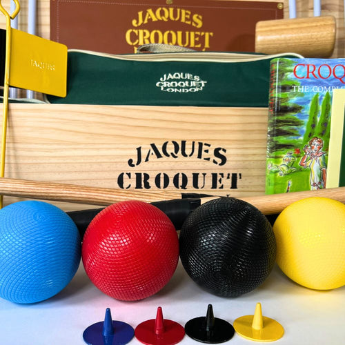 Croquet set with balls and mallets in front of a Jaques Croquet box. 