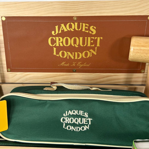 Jacques Croquet London green croquet bag with brown leather cover on a wooden background 