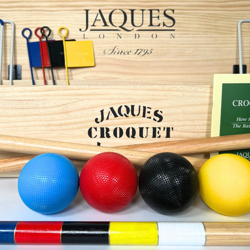 Croquet set with balls and mallets in front of a Jaques London branded box.  
