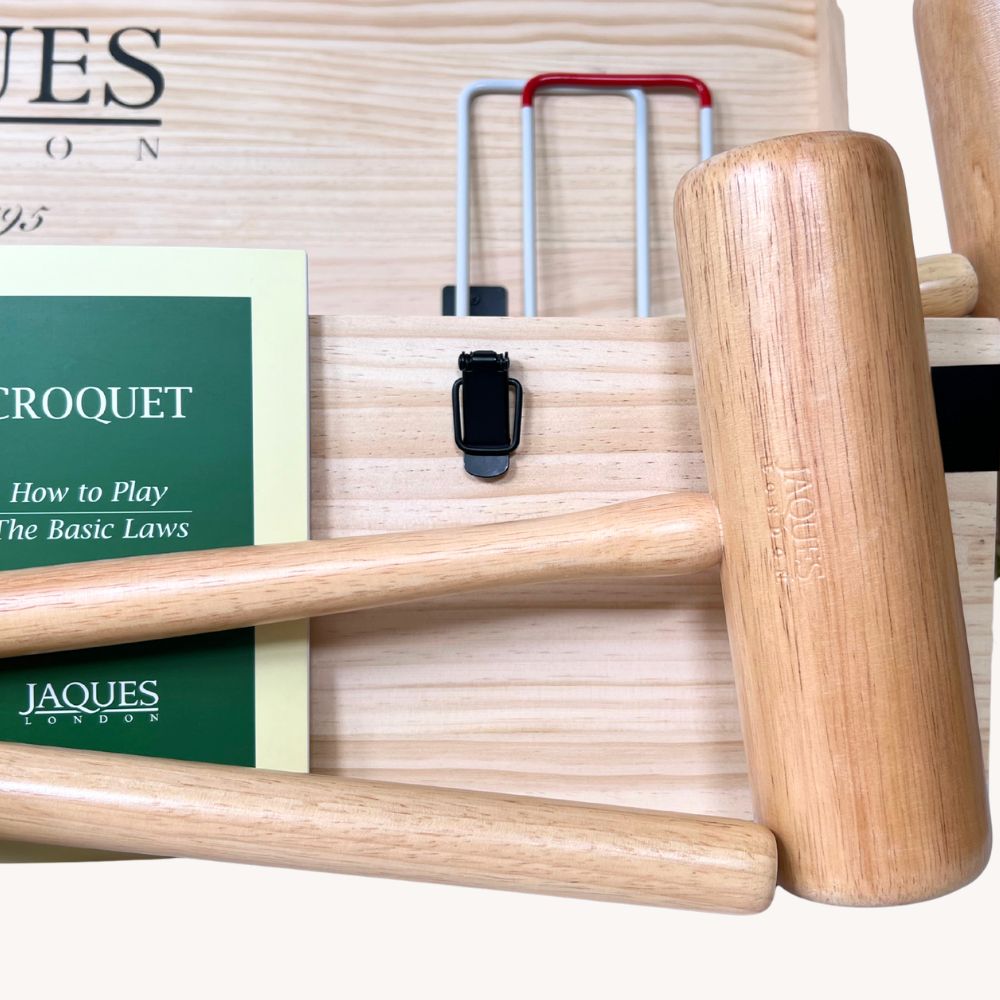Wooden croquet mallets with a 'How to Play Croquet' guide on a wooden stand.  
