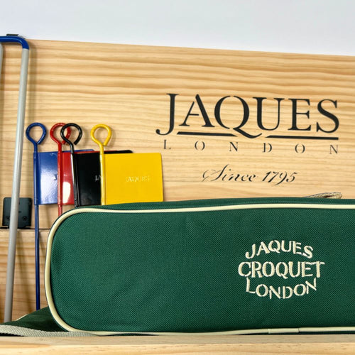 Croquet set with green case and accessories on a wooden surface, featuring Jaques London branding.  