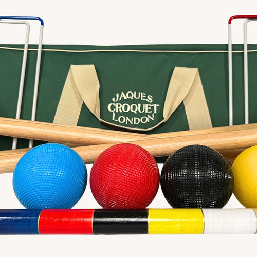 Croquet set with colorful balls and mallets in front of a Jaques Croquet London bag.  