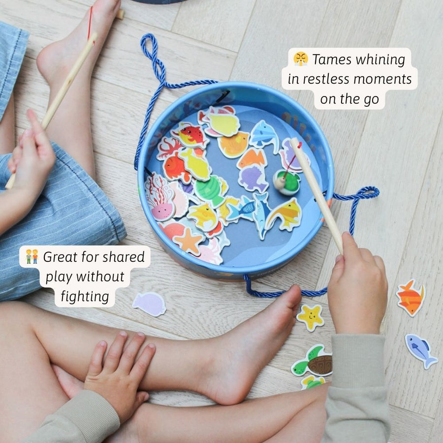 Children playing with a magnetic fishing game on a wooden floor. [fill]