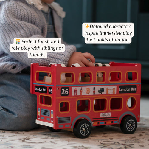 Close-up of a child sitting on the floor with a red London bus toy filled with wooden figures, with text highlighting detailed characters that inspire immersive play. 