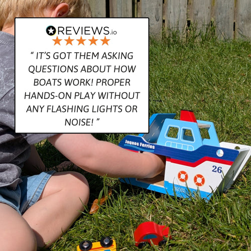 Child playing with the wooden boat on grass, placing or adjusting a small peg figure near the boat to demonstrate hands-on play. 