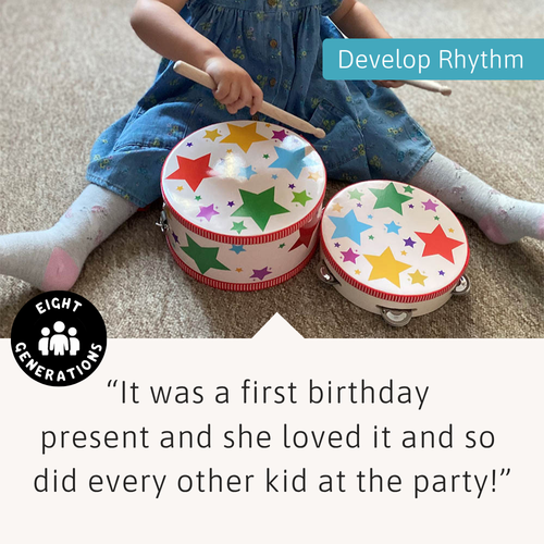 Child sitting on floor playing with Jaques toy drum, with overlaid text ‘Develop Rhythm’ and a positive customer review. 