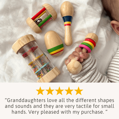 Colorful wooden toys on a soft surface with a child's hand holding one toy.