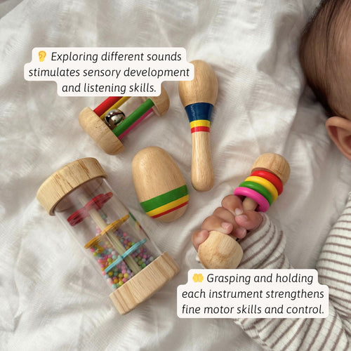 Baby lying on a soft white blanket holding a wooden rattle and clear shaker tube filled with colorful beads, with text about strengthening fine motor skills and control. 