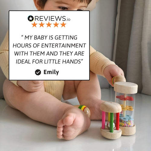 Baby sitting on the floor holding two wooden shaker instruments, with a five-star review overlay stating they are ideal for little hands and provide hours of entertainment. 