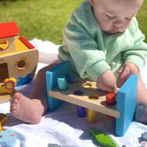 Baby playing with wooden hammering bench 