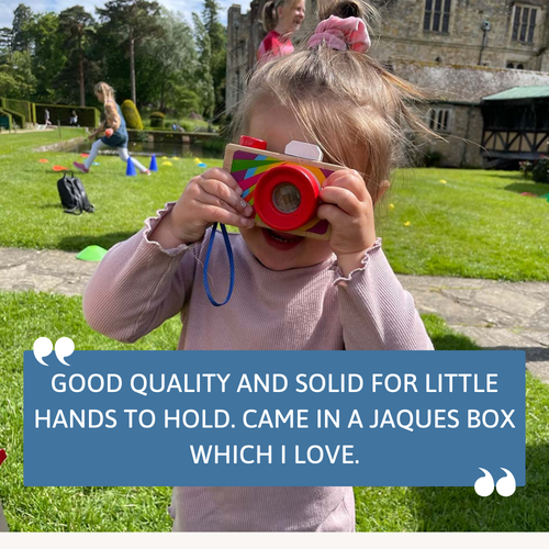 Child holding a colourful toy camera outdoors with text overlay.