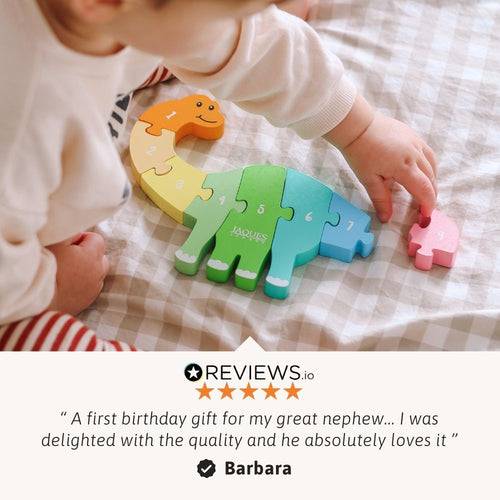 Child playing with a colourful dinosaur-shaped puzzle toy on a checkered blanket.. 