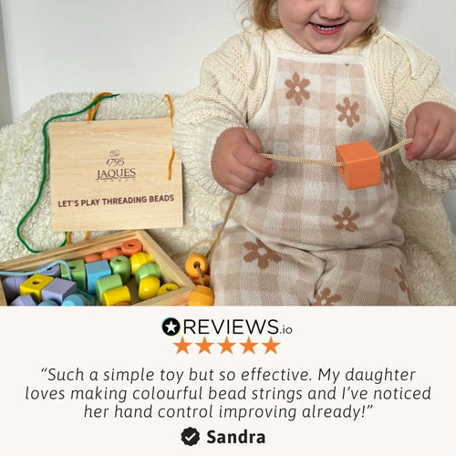 A young child proudly holding their completed bead string creation 