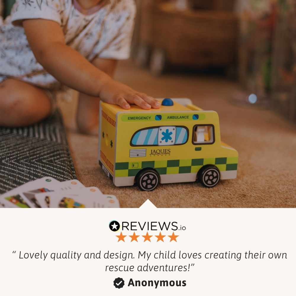 Child playing with a wooden ambulance toy and learning cards during imaginative emergency play. 