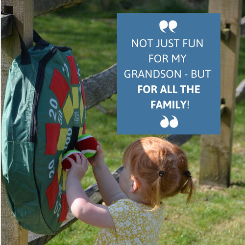 Toddler placing target balls on the hanging inflatable dartboard outdoors, with blue text box saying “Not just fun for my grandson – but for all the family!” 
