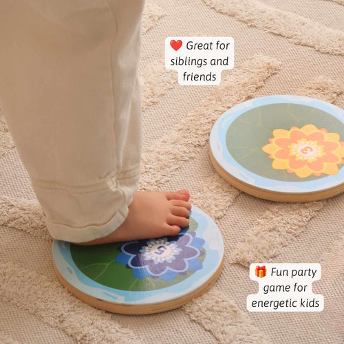 Two round wooden balance board games with colourful floral designs are shown on a textured beige rug. One board is being stepped on by a child's bare foot, with text overlays highlighting its suitability for siblings, friends, and as a party game. 