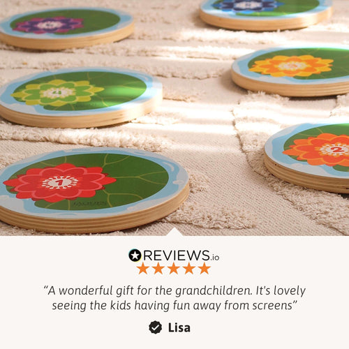 Round wooden board games with colourful lotus flower illustrations, arranged on a beige textured rug. A review section at the bottom features a five-star review from Reviews10 with the name Lisa. 