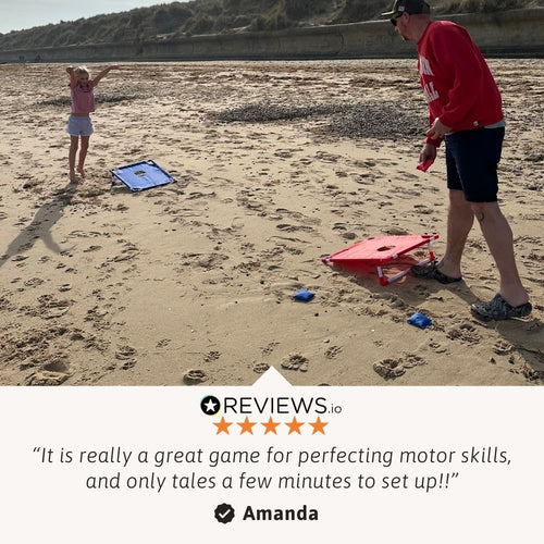 Child tossing a bean bag toward the cornhole board during a beach game. 