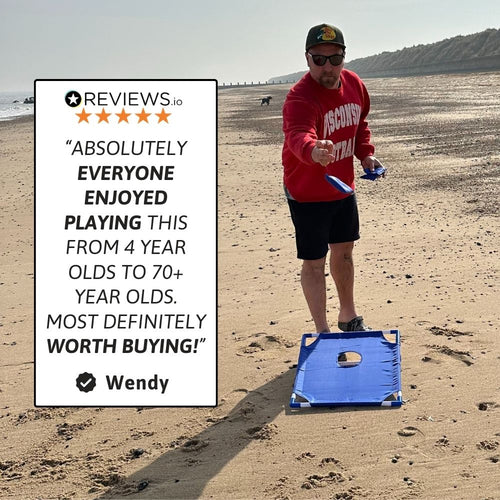 Man tossing a bean bag toward the cornhole board during a beach game. 