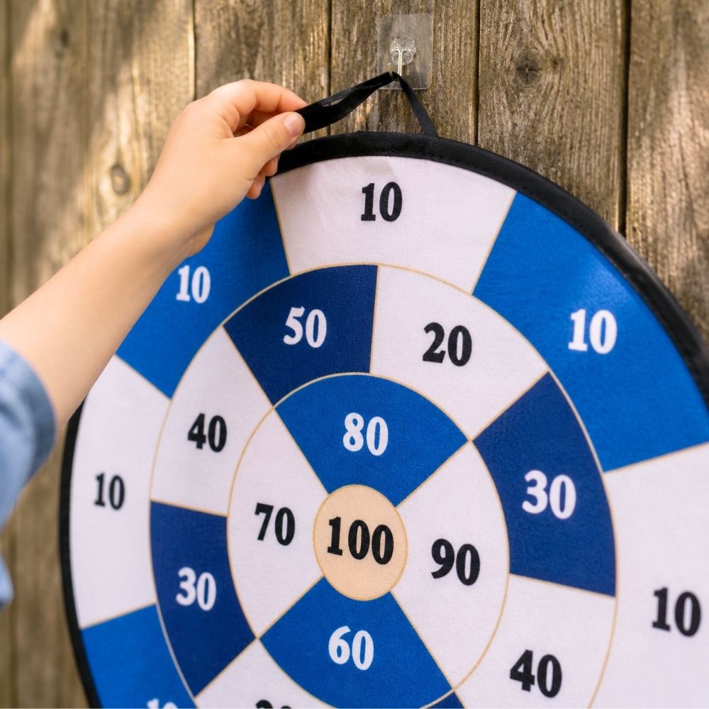 Hand holding a blue and white dartboard against a wooden background  