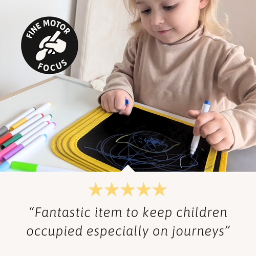 Child drawing on a magnetic drawing board with markers, surrounded by more markers.