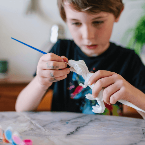 Boy painting dinosaur  