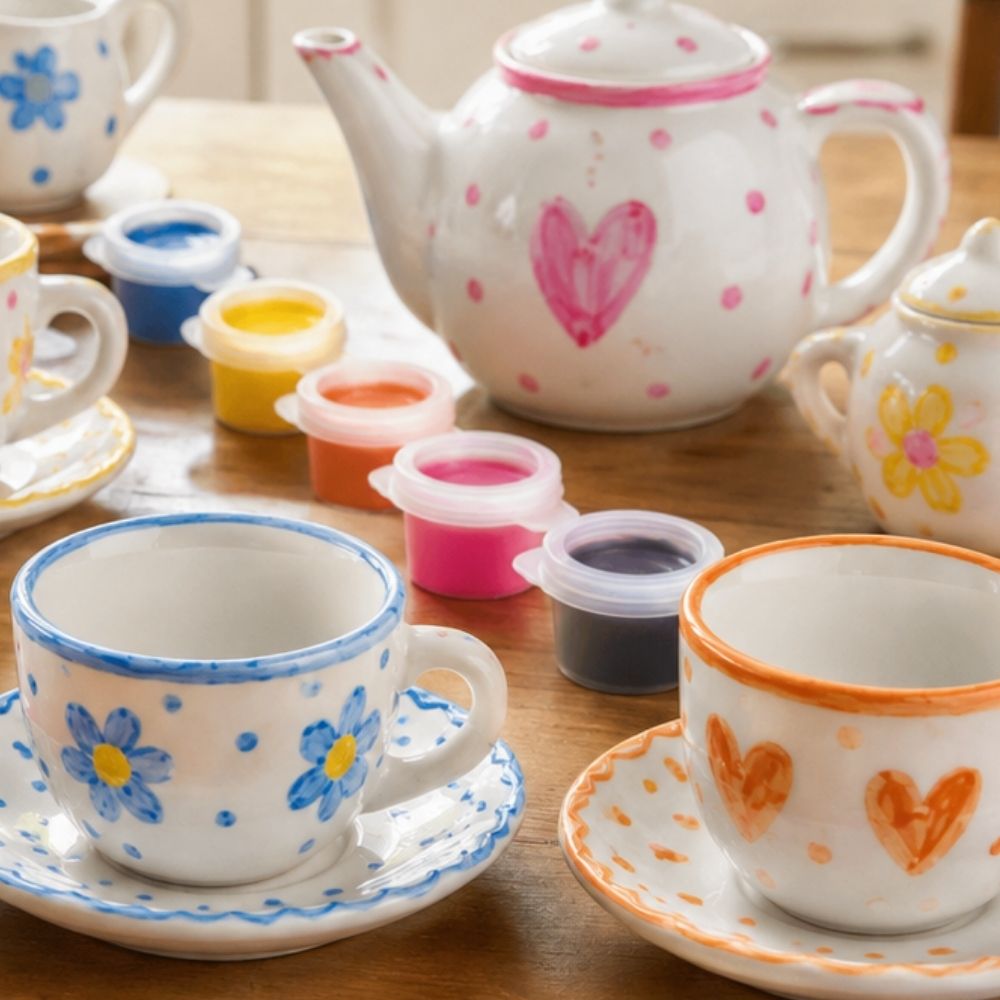 Collection of ceramic teacups and teapot with decorative designs on a wooden surface. 