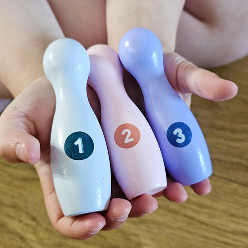 Colourful wooden baby skittles in hands 