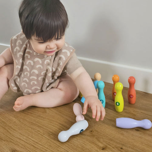 Child playing with colourful wooden baby skittles 