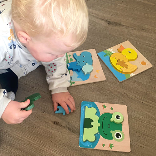 Child playing with wooden animal puzzles on a wooden floor 