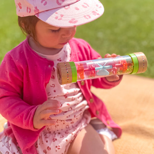 Child holding a colorful sand timer outdoors on a sunny day 