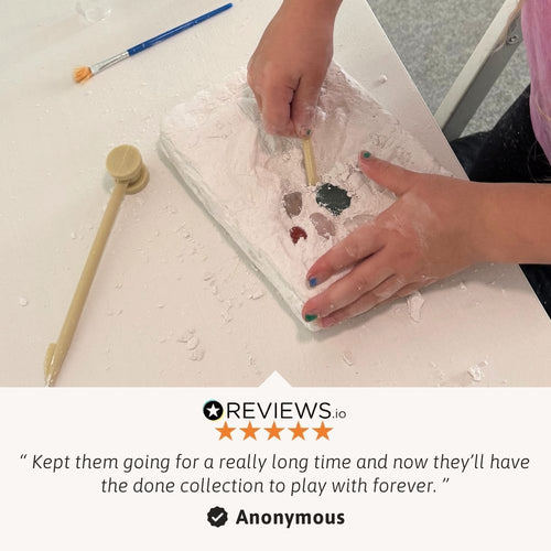 Hands working with a material on a white surface, with a paintbrush and mallet nearby. Anonymous review text at the bottom. 