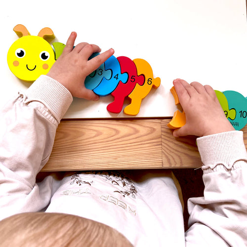 Children playing with colourful number puzzle on a wooden table 