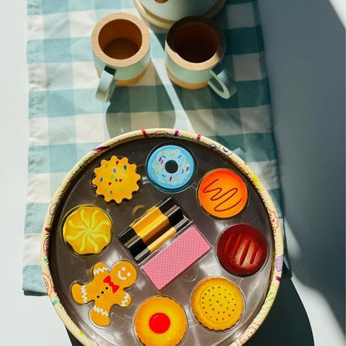  Box of biscuits with lid off next to wooden cups on a blue picnic blanket