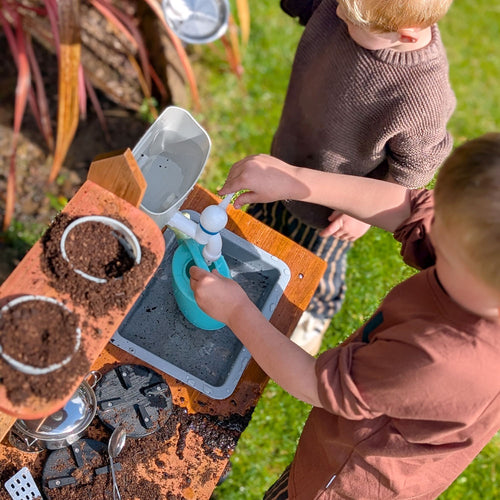 Children playing with wooden mud kitchen sink 
