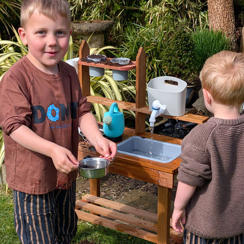 Children playing with wooden mud kitchen 