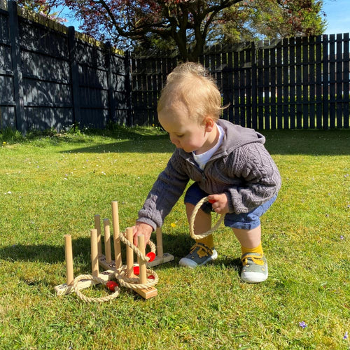  Boy kneeling down to pick up quoit on board in garden 