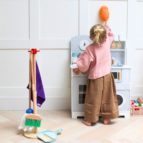  Girl playing with duster brush dusting the wall 