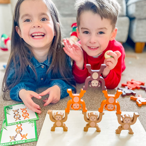 Two children playing with monkey toys on a table.  