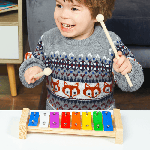 Child playing with a colorful wooden xylophone indoors  