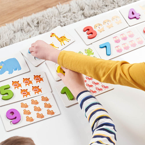 Children playing with educational number and animal cards on a wooden floor.  
